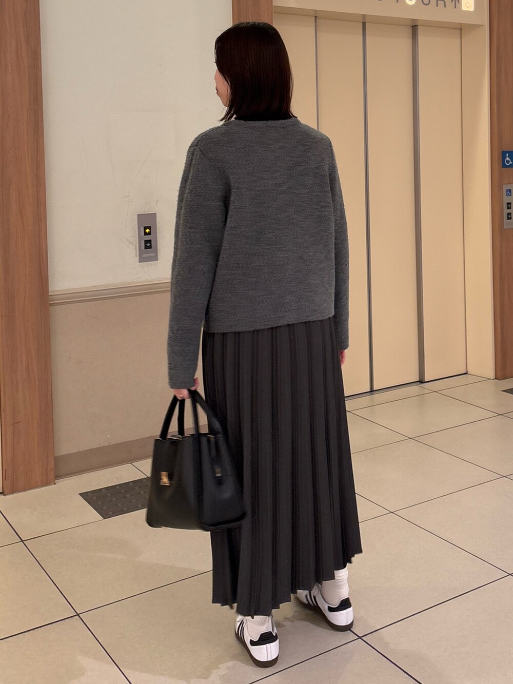 グレー系のその他アウター、ブラック系のニット/セーター、グレー系のスカートを着用したレディースの冬コーディネートの3枚目の写真