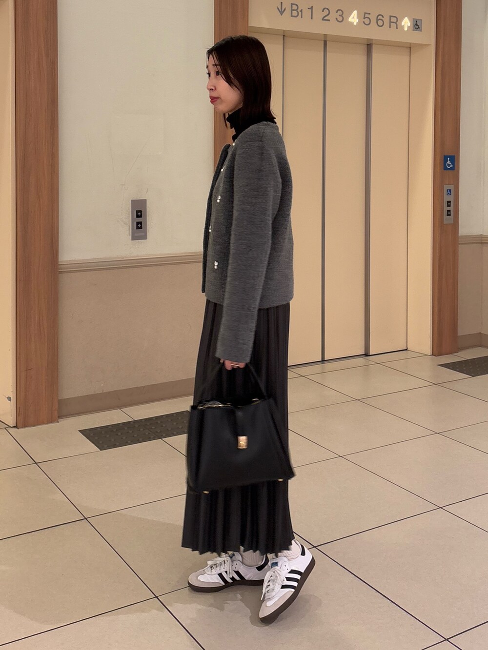 グレー系のその他アウター、ブラック系のニット/セーター、グレー系のスカートを着用したレディースの冬コーディネートの2枚目の写真