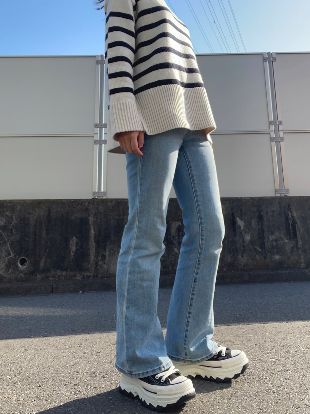 ブルー系のデニムパンツ、ブルー系のデニムジャケット、ホワイト系のニット/セーターを着用したレディースの春コーディネートの2枚目の写真