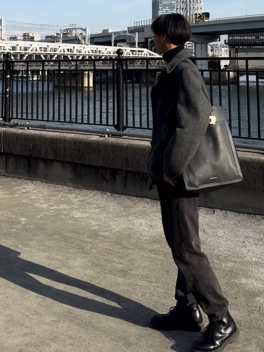 ブラック系のトートバッグ、ブラック系のデニムパンツ、ブラック系のニット/セーターを着用したメンズの春コーディネートの2枚目の写真