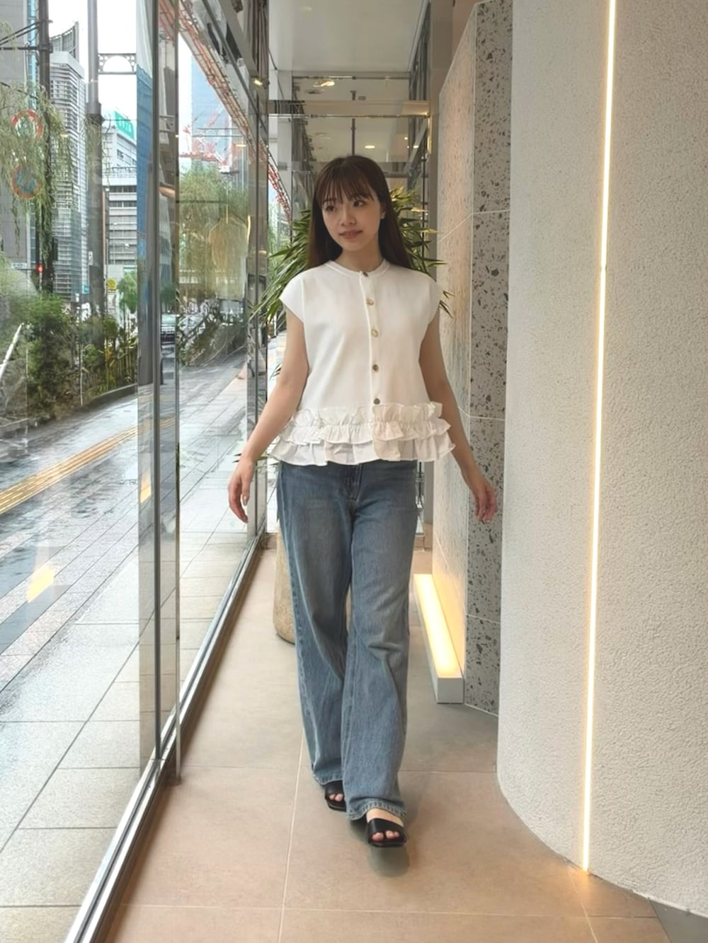 ホワイト系のベスト、ブルー系のデニムパンツ、ブラック系のサンダルを着用したレディースの夏コーディネートの2枚目の写真