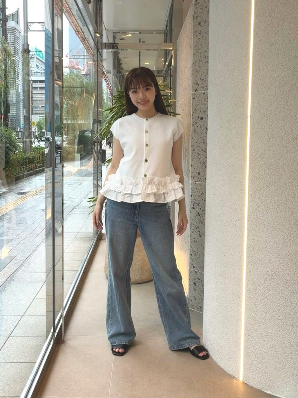 ホワイト系のベスト、ブルー系のデニムパンツ、ブラック系のサンダルを着用したレディースの夏コーディネートの4枚目の写真