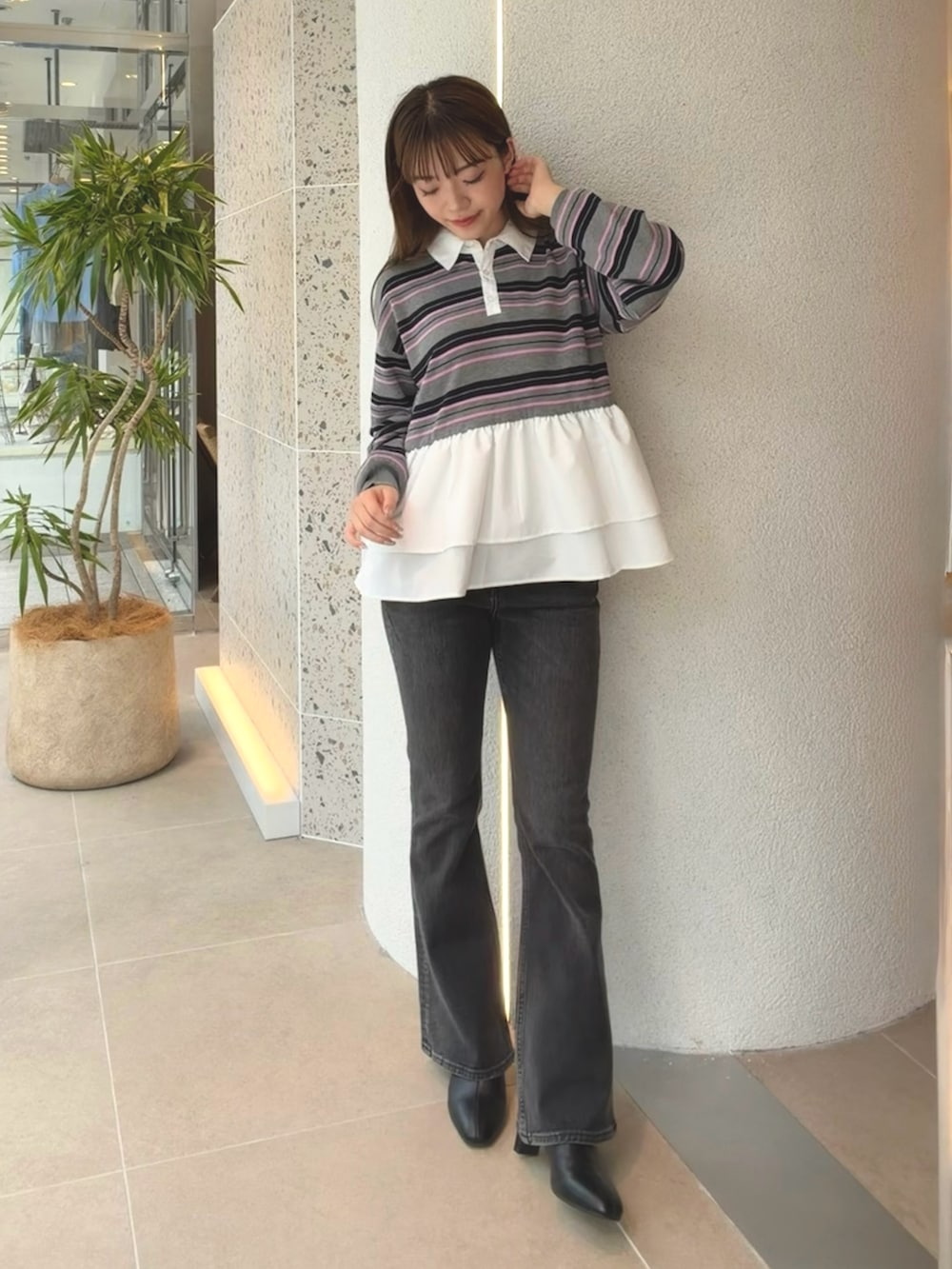 グレー系のニット/セーター、ブラック系のデニムパンツ、ブラック系のブーツを着用したレディースの秋コーディネートの2枚目の写真