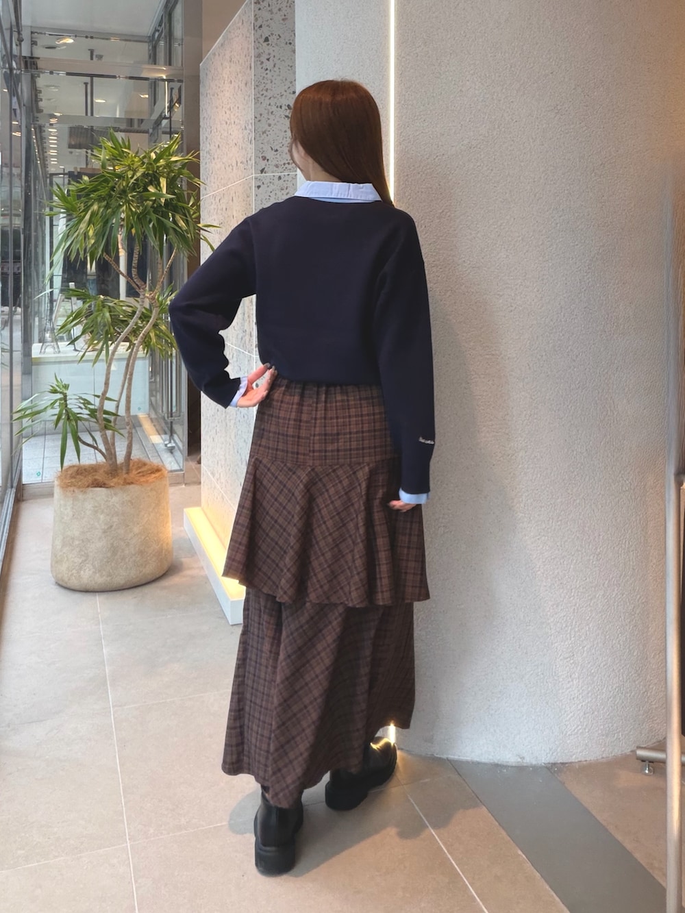 ブルー系のニット/セーター、ブラウン系のスカート、ブラック系のブーツを着用したレディースの秋コーディネートの8枚目の写真