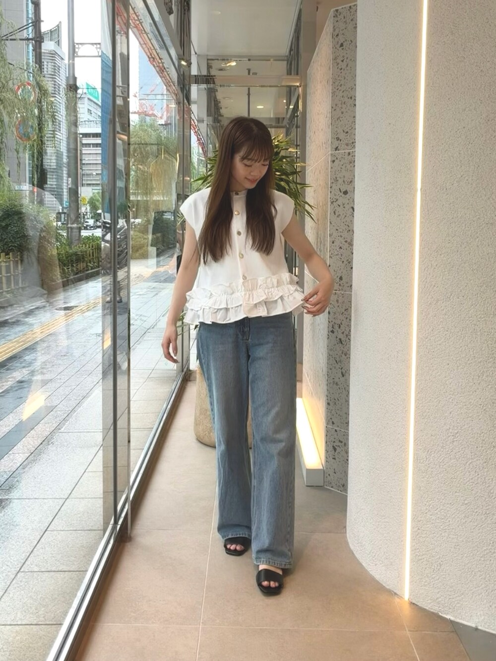 ホワイト系のベスト、ブルー系のデニムパンツ、ブラック系のサンダルを着用したレディースの夏コーディネートの3枚目の写真