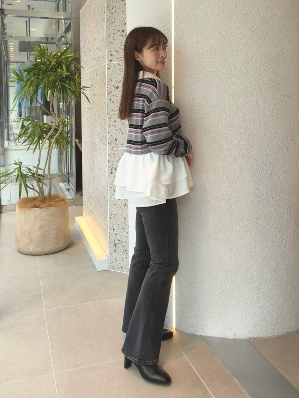 グレー系のニット/セーター、ブラック系のデニムパンツ、ブラック系のブーツを着用したレディースの秋コーディネートの7枚目の写真