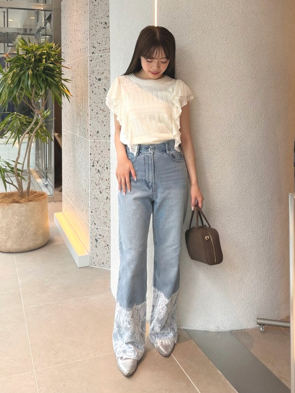 ホワイト系のニット/セーター、ブルー系のデニムパンツ、ベージュ系のボストンバッグを着用したレディースの夏コーディネートの3枚目の写真