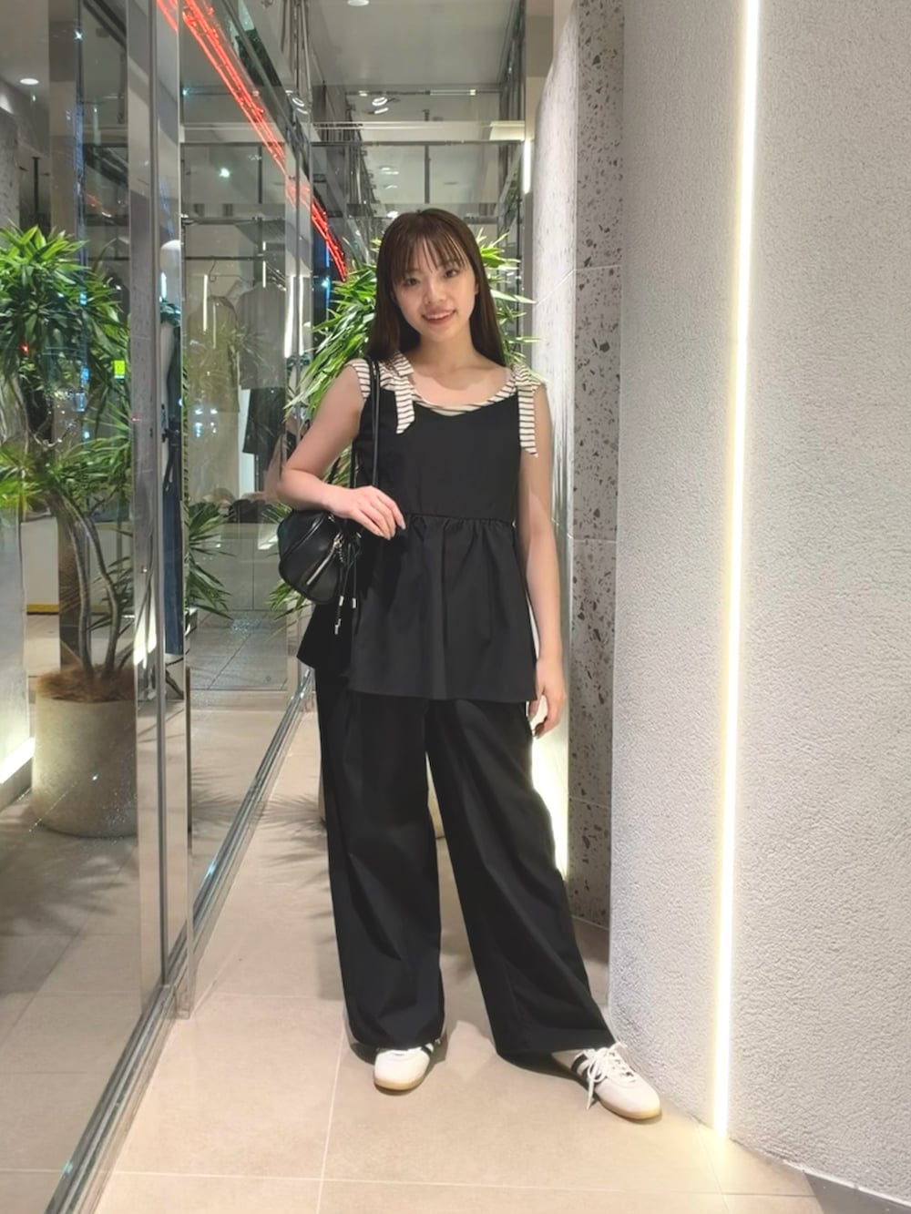 ホワイト系のTシャツ/カットソー、ホワイト系のスニーカー、ブラック系のボストンバッグを着用したレディースの夏コーディネートの3枚目の写真