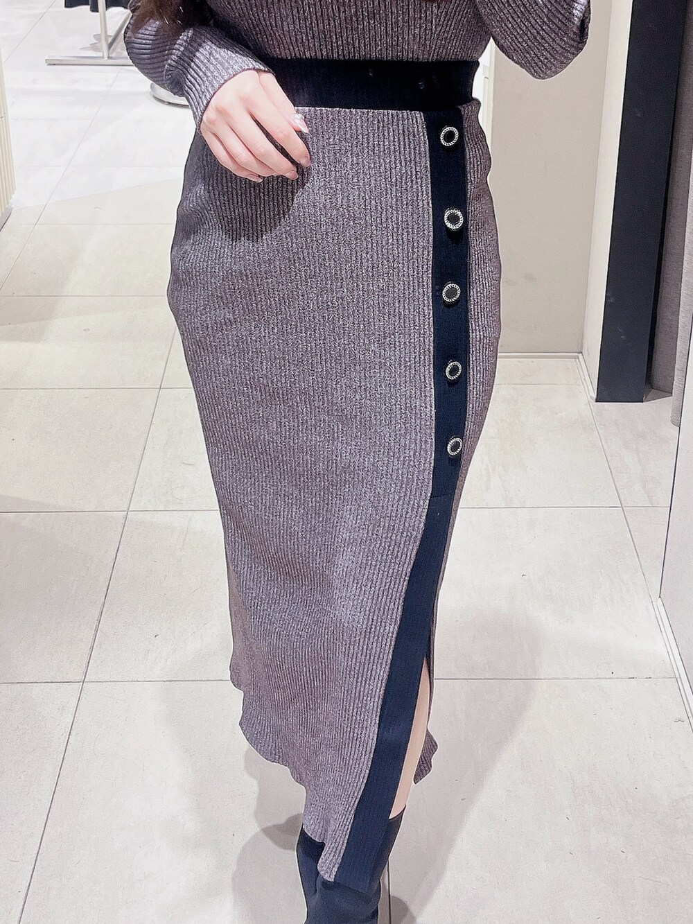 グレー系のTシャツ/カットソー、グレー系のスカート、ブラック系のブーツを着用したレディースの冬コーディネートの5枚目の写真