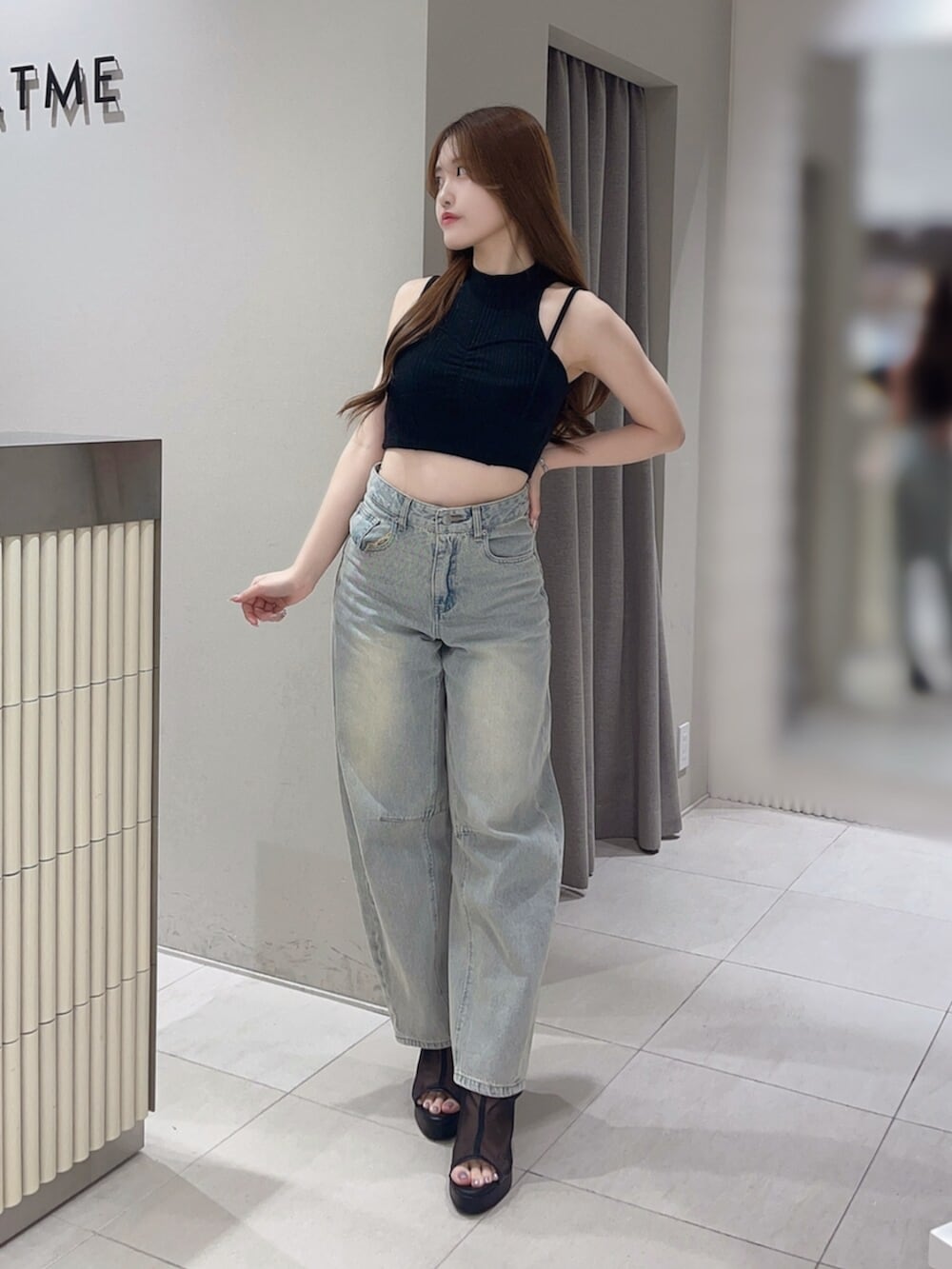 ブラック系のタンクトップ、ブルー系のデニムパンツ、ブラック系のサンダルを着用したレディースの夏コーディネートの2枚目の写真