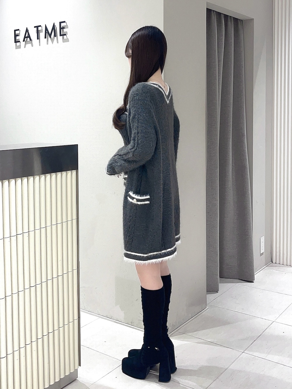 グレー系のワンピース、ブラック系のブーツを着用したレディースの冬コーディネートの2枚目の写真