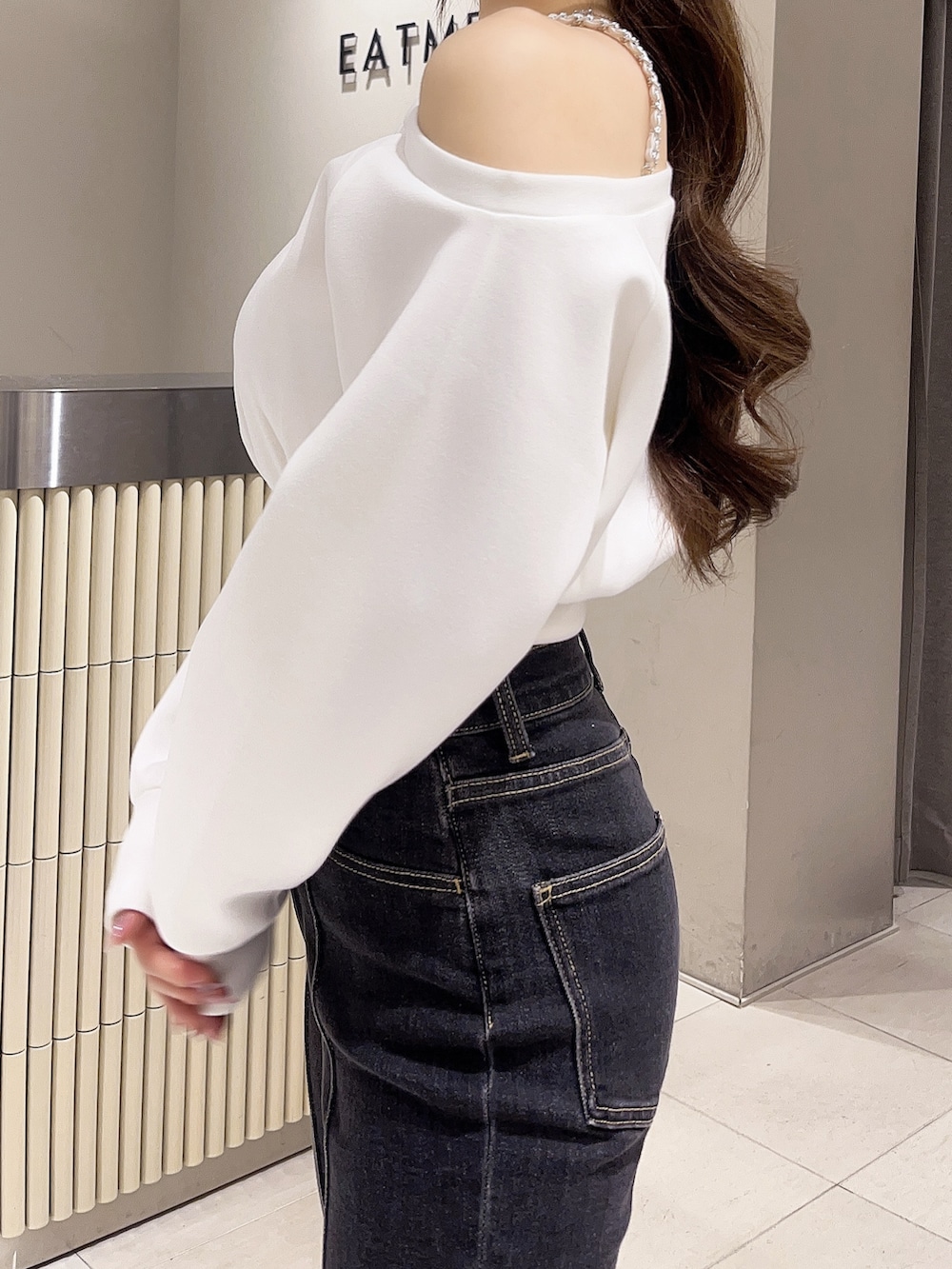 ホワイト系のスウェット、ブラック系のデニムパンツ、ブラック系のブーツを着用したレディースの春コーディネートの5枚目の写真