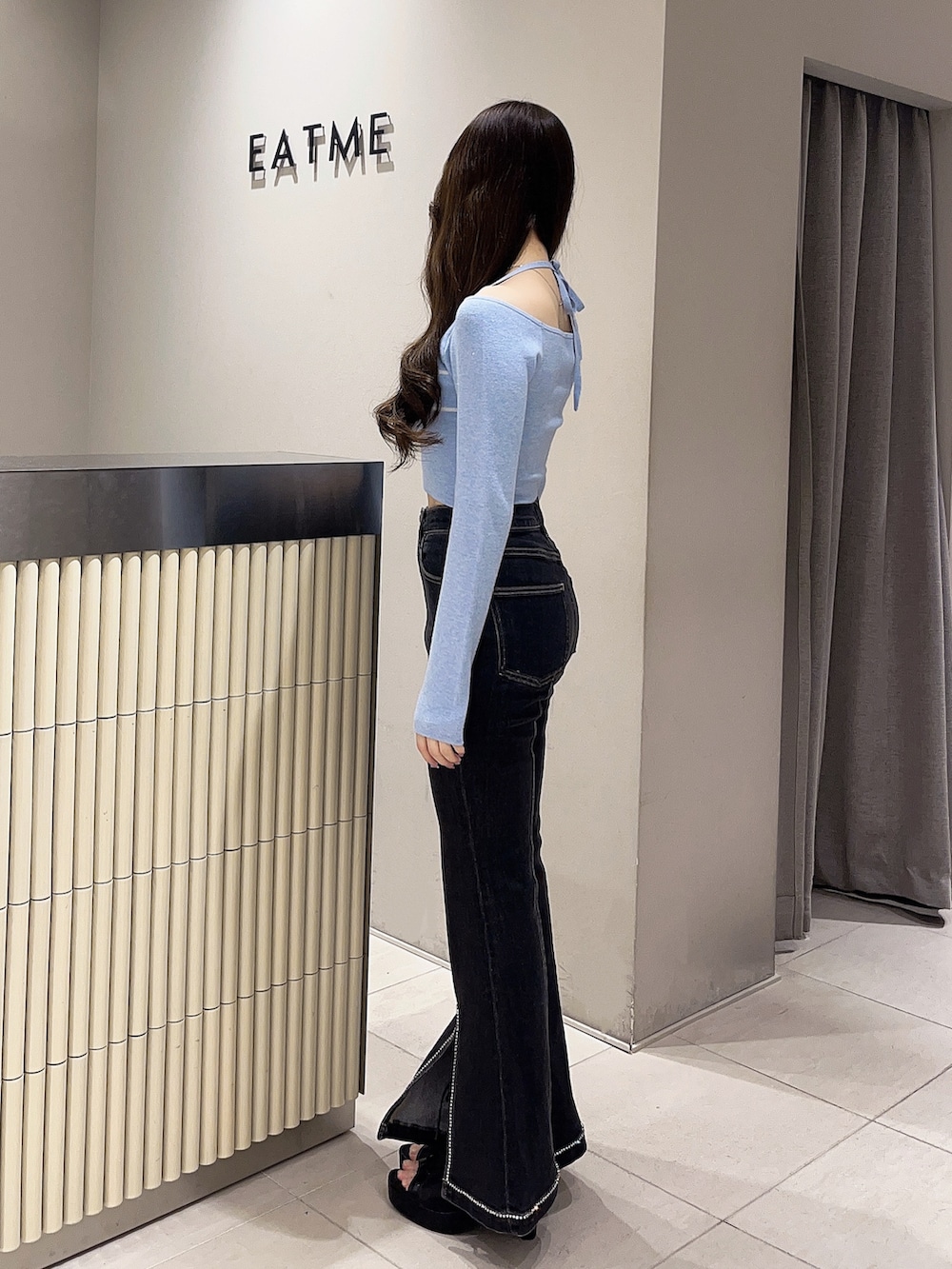 ブルー系のニット/セーター、ブラック系のデニムパンツ、ブラック系のブーツを着用したレディースの春コーディネートの2枚目の写真