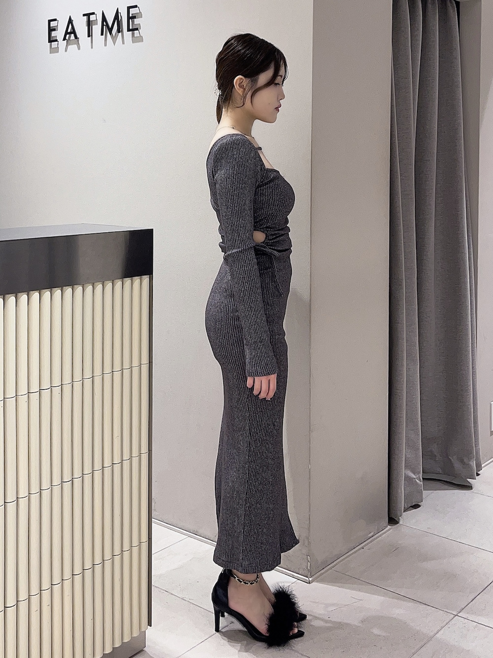 グレー系のワンピース、ブラック系のサンダルを着用したレディースの春コーディネートの2枚目の写真