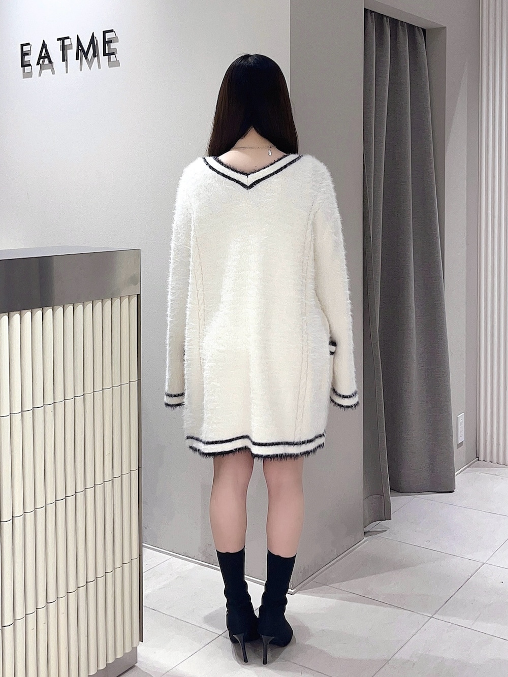 ホワイト系のワンピース、ブラック系のブーツを着用したレディースの冬コーディネートの3枚目の写真