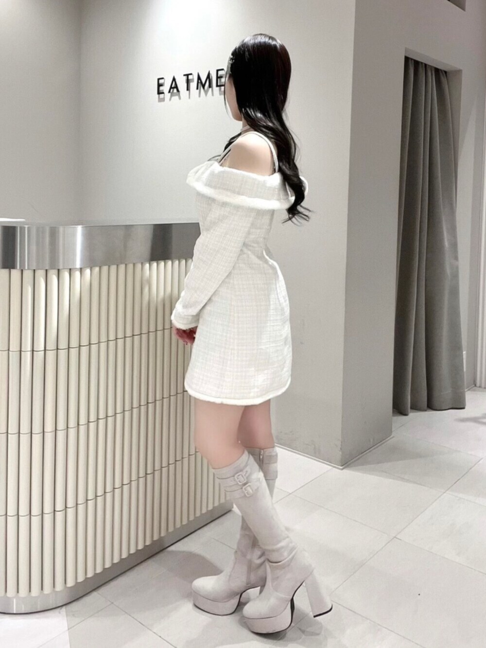 ホワイト系のワンピース、ホワイト系のブーツ、シルバー系のネックレスを着用したレディースの冬コーディネートの2枚目の写真