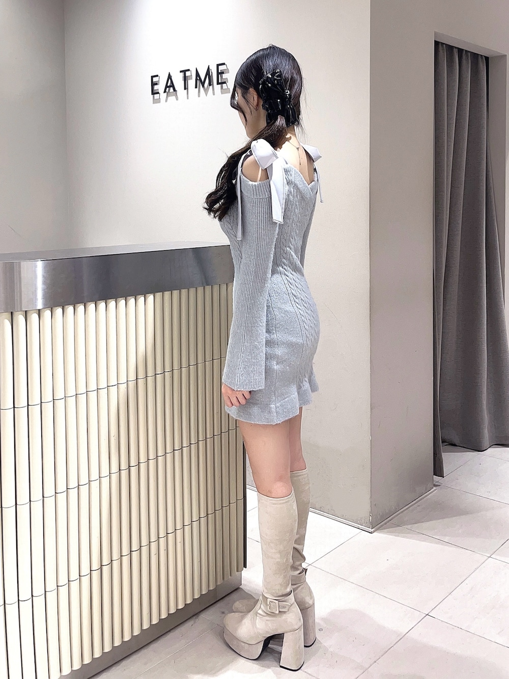 グレー系のワンピース、ホワイト系のブーツ、ブラック系のバレッタ/ヘアクリップを着用したレディースの冬コーディネートの2枚目の写真