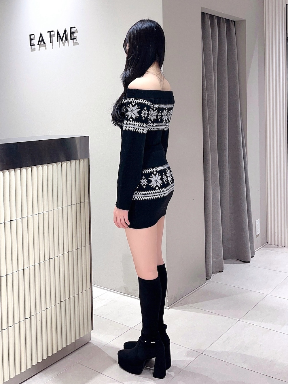 ブラック系のニット/セーター、ブラック系のスカート、ブラック系のブーツを着用したレディースの秋コーディネートの3枚目の写真