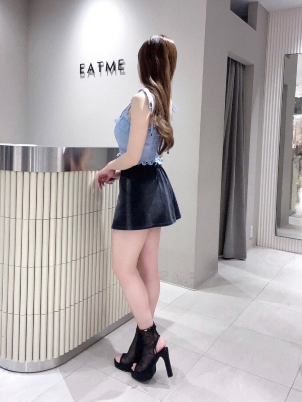 ブルー系のキャミソール、ブラック系のデニムスカート、ブラック系のサンダルを着用したレディースの春コーディネートの3枚目の写真