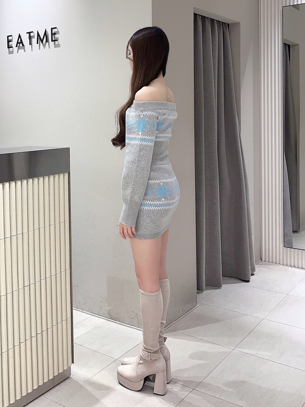 グレー系のニット/セーター、グレー系のスカート、ホワイト系のブーツを着用したレディースの秋コーディネートの2枚目の写真