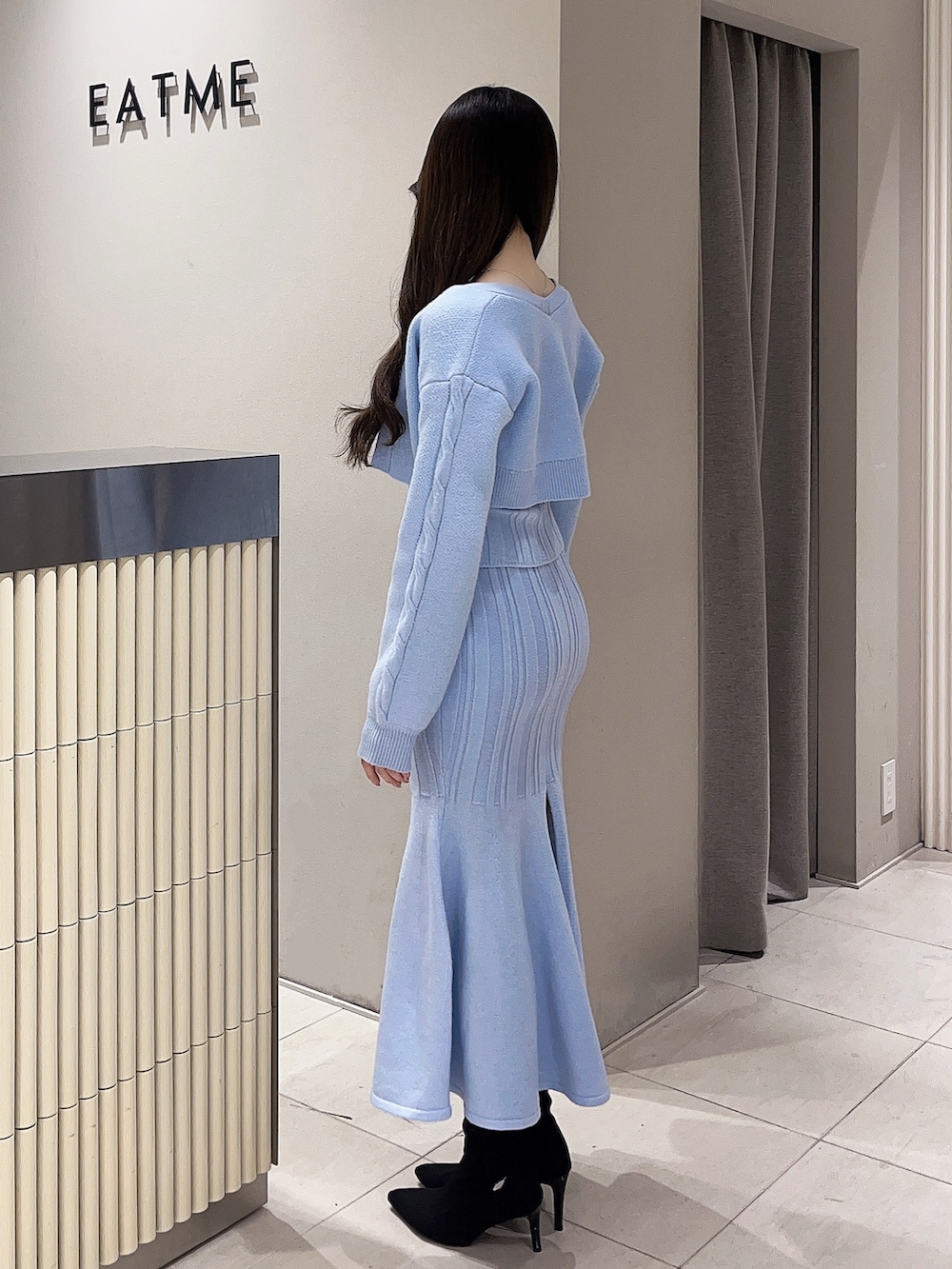 ブルー系のニット/セーター、ブルー系のスカート、ブラック系のブーツを着用したレディースの冬コーディネートの2枚目の写真