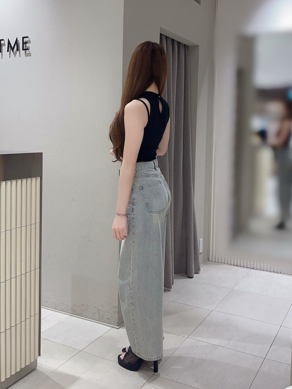 ブラック系のタンクトップ、ブルー系のデニムパンツ、ブラック系のサンダルを着用したレディースの夏コーディネートの3枚目の写真