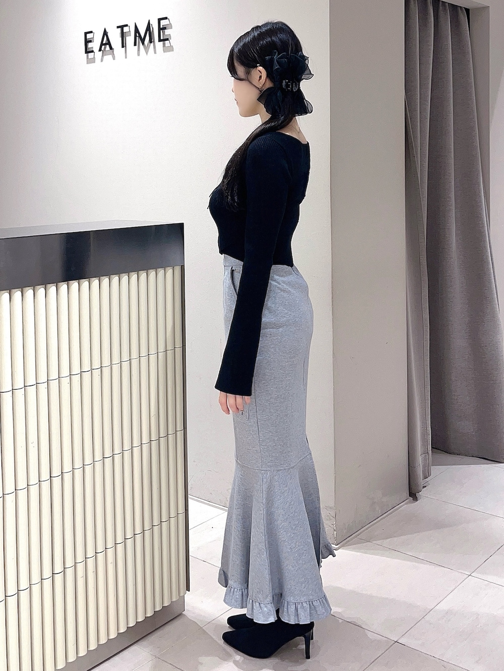 ブラック系のニット/セーター、グレー系のスカート、ブラック系のブーツを着用したレディースの秋コーディネートの3枚目の写真