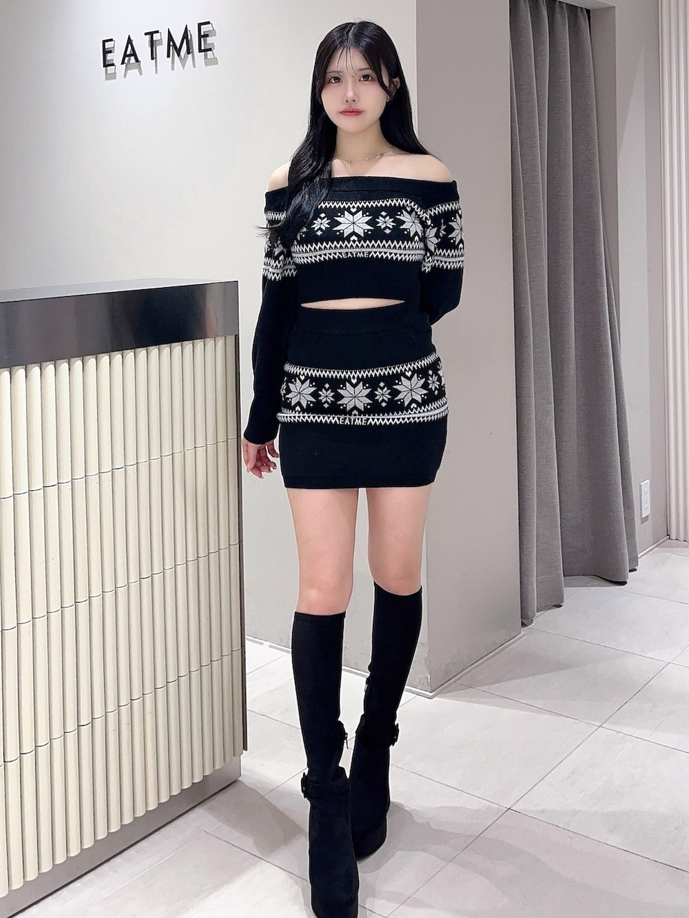 ブラック系のニット/セーター、ブラック系のスカート、ブラック系のブーツを着用したレディースの秋コーディネートの2枚目の写真