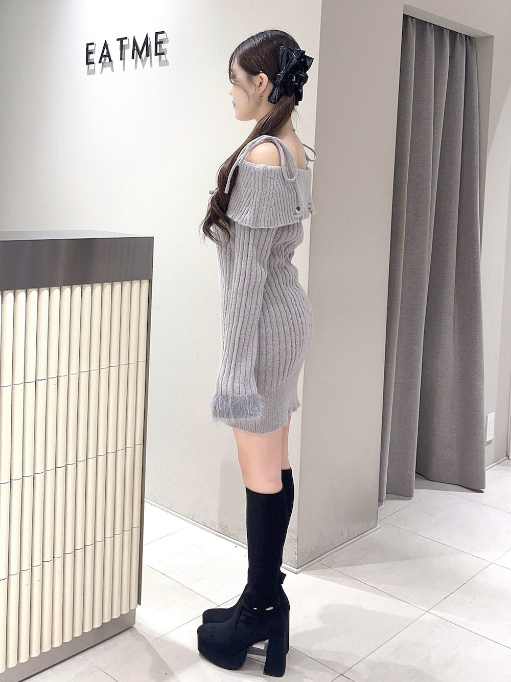 グレー系のワンピース、ブラック系のブーツ、ブラック系のバレッタ/ヘアクリップを着用したレディースの秋コーディネートの2枚目の写真