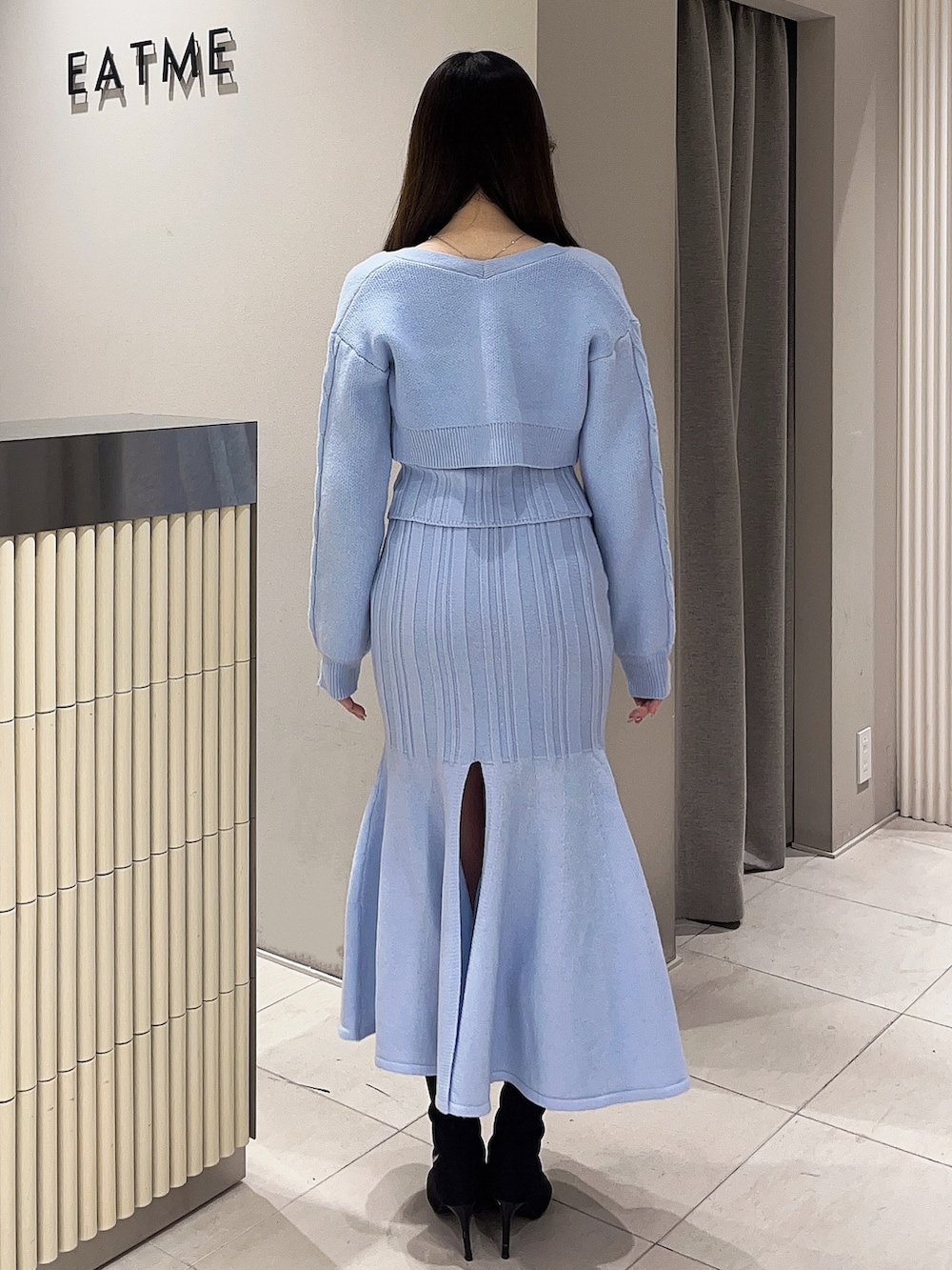 ブルー系のニット/セーター、ブルー系のスカート、ブラック系のブーツを着用したレディースの冬コーディネートの3枚目の写真