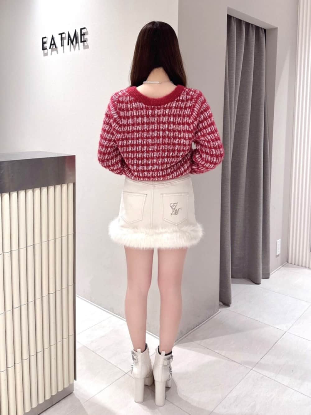 レッド系のカーディガン/ボレロ、ホワイト系のデニムスカート、ホワイト系のブーツを着用したレディースの冬コーディネートの3枚目の写真