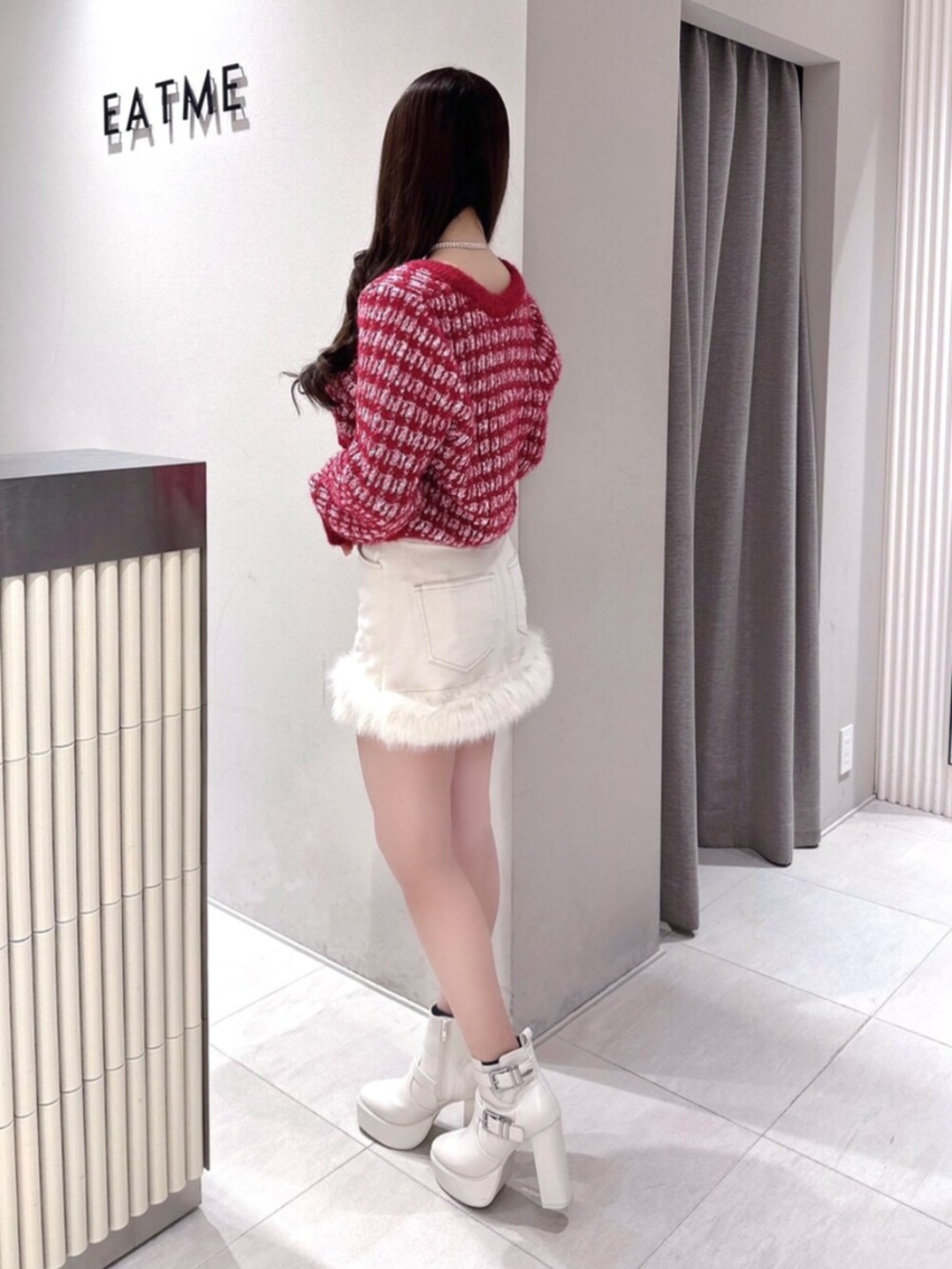 レッド系のカーディガン/ボレロ、ホワイト系のデニムスカート、ホワイト系のブーツを着用したレディースの冬コーディネートの2枚目の写真