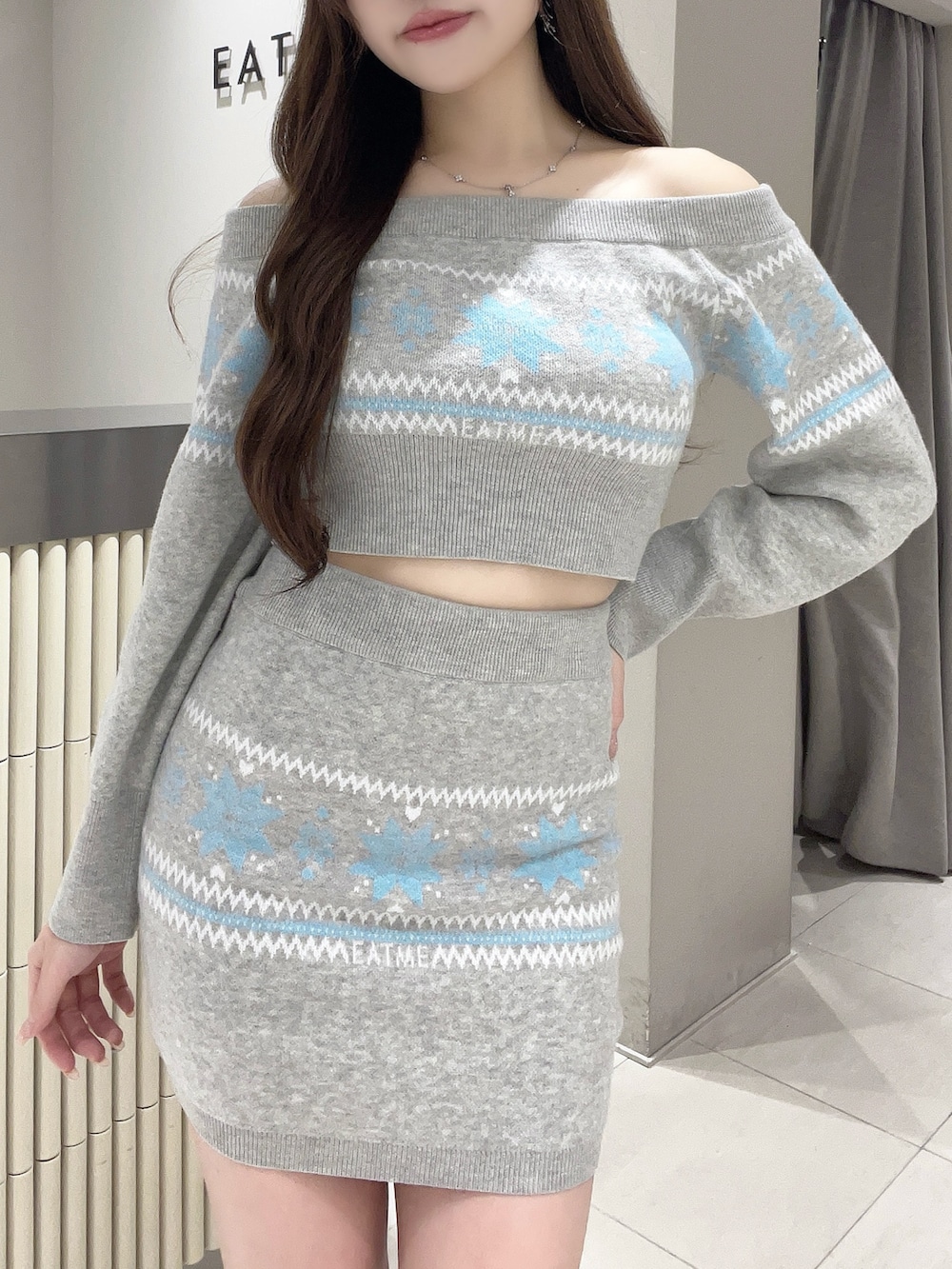 グレー系のニット/セーター、グレー系のスカート、ホワイト系のブーツを着用したレディースの秋コーディネートの4枚目の写真