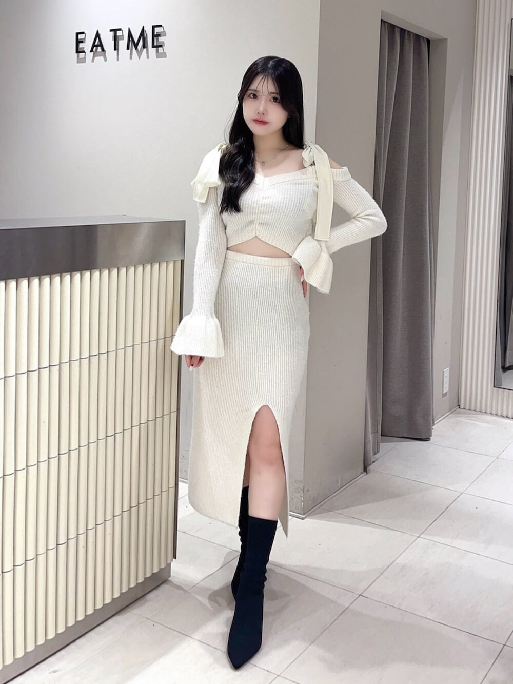 ホワイト系のワンピース、ブラック系のブーツを着用したレディースの冬コーディネートの2枚目の写真