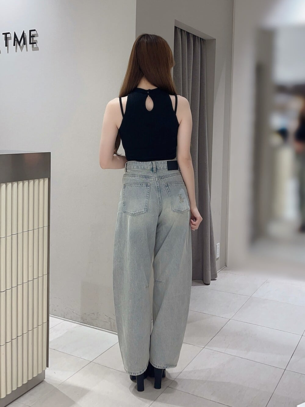 ブラック系のタンクトップ、ブルー系のデニムパンツ、ブラック系のサンダルを着用したレディースの夏コーディネートの4枚目の写真