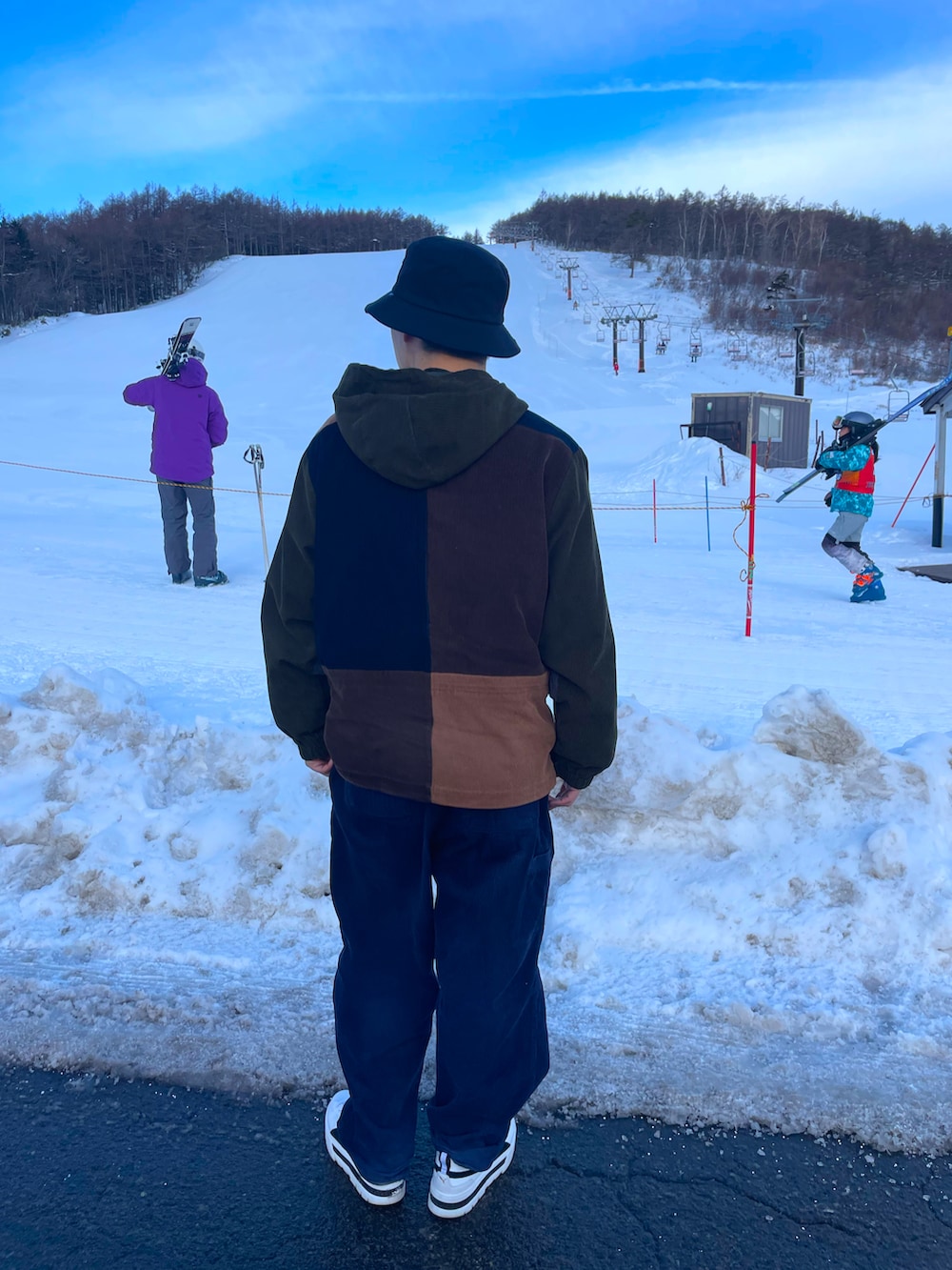 グリーン系のマウンテンパーカー、ブルー系のチノパンツ、ブラック系のスニーカーを着用したメンズの冬コーディネートの2枚目の写真