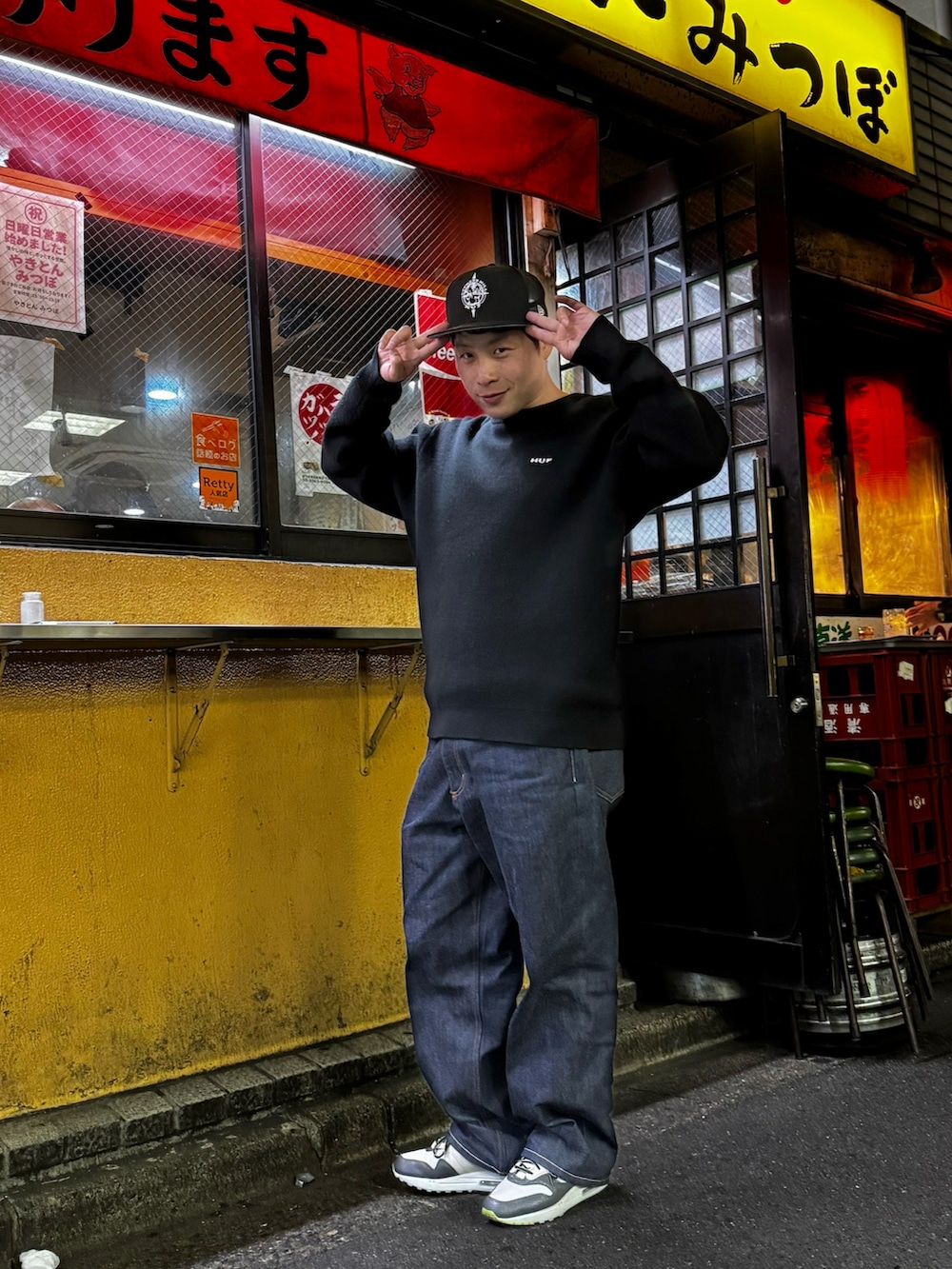 グレー系のスニーカー、ブラック系のニット/セーター、ブルー系のデニムパンツを着用したメンズの春コーディネートの2枚目の写真