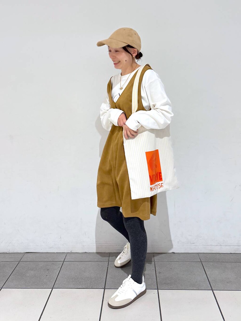 イエロー系のトートバッグ、ホワイト系のTシャツ/カットソー、ホワイト系のスニーカーを着用したレディースの冬コーディネートの2枚目の写真