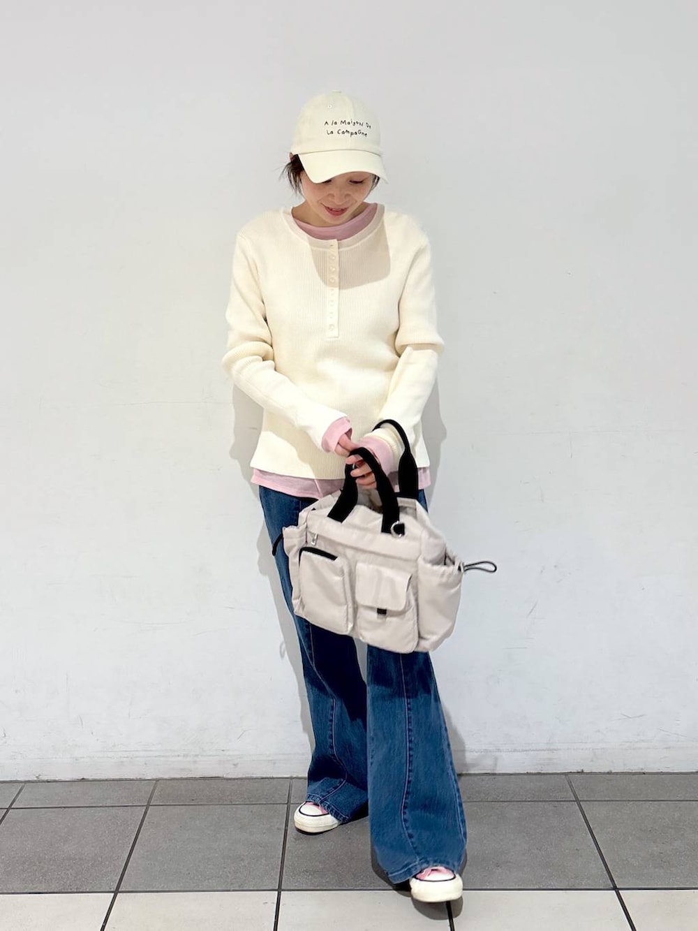 グレー系のトートバッグ、ホワイト系のニット/セーター、ブルー系のデニムパンツを着用したレディースの冬コーディネートの3枚目の写真