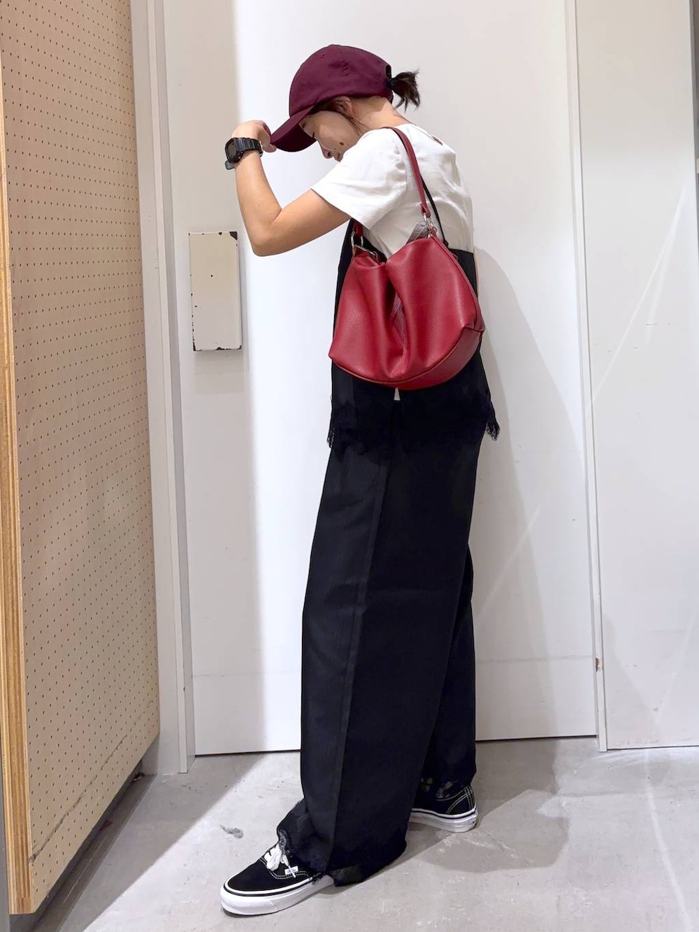 ブラック系のスラックス、ブラック系のキャミソール、レッド系のショルダーバッグを着用したレディースの夏コーディネートの3枚目の写真