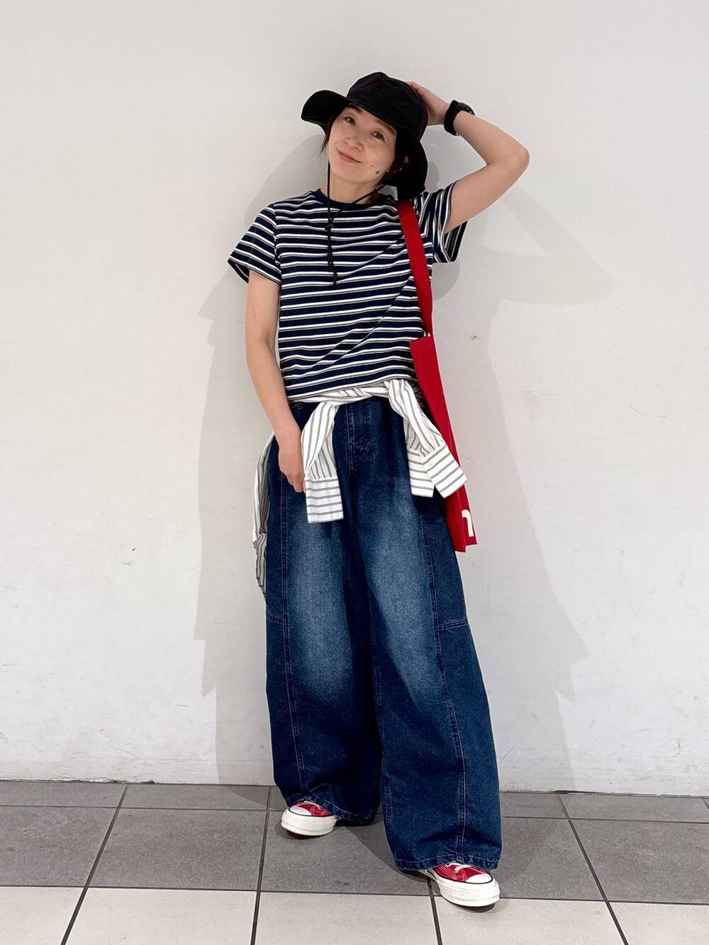 レッド系のトートバッグ、ブルー系のデニムパンツ、ホワイト系のシャツ/ブラウスを着用したレディースの春コーディネートの5枚目の写真