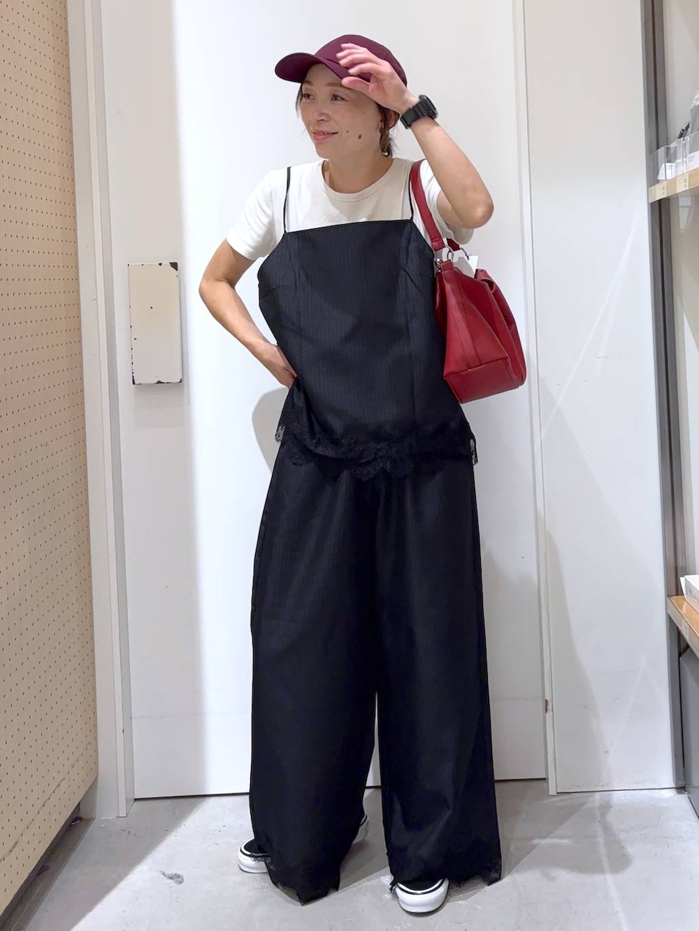 ブラック系のスラックス、ブラック系のキャミソール、レッド系のショルダーバッグを着用したレディースの夏コーディネートの2枚目の写真
