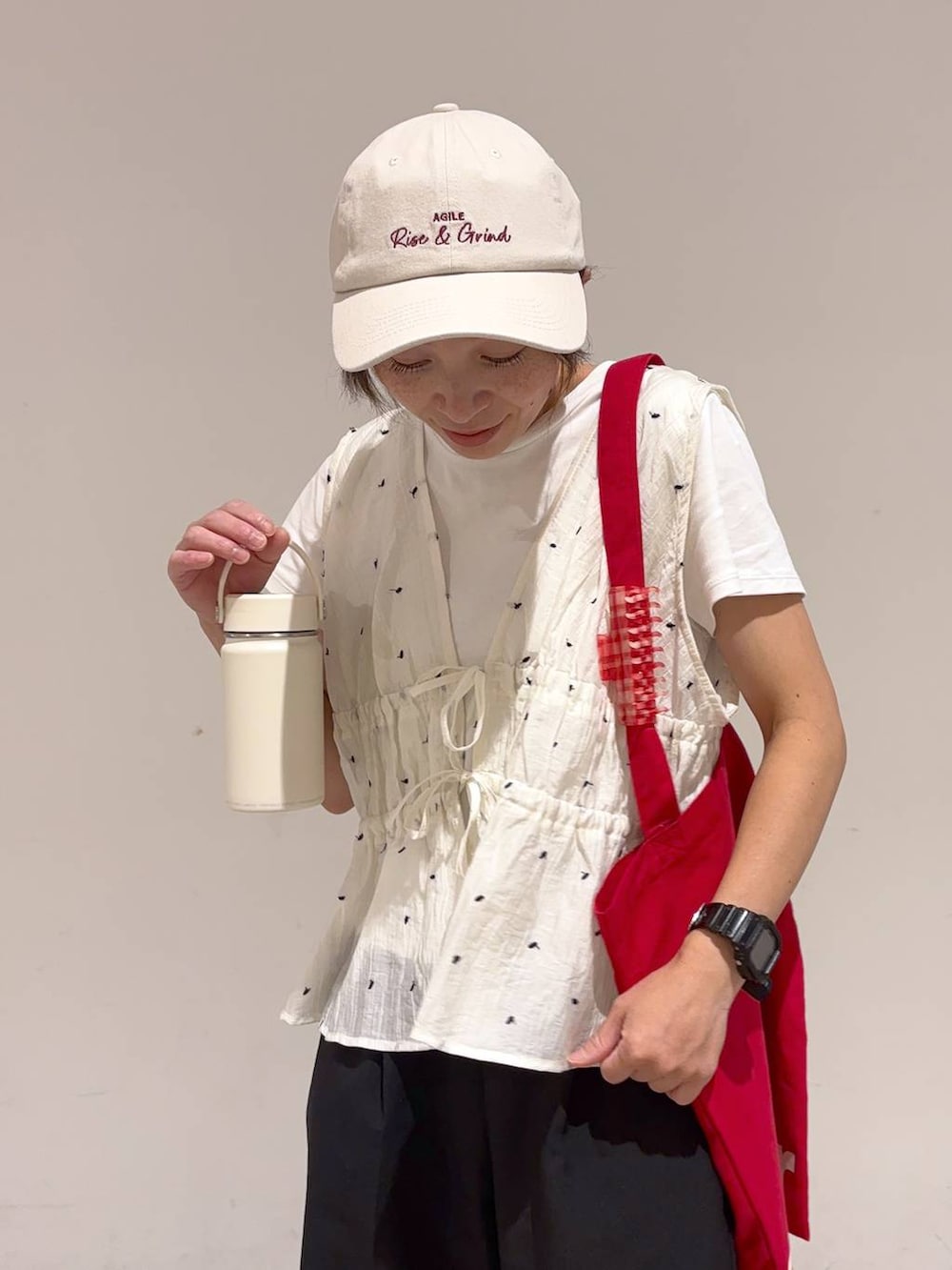 レッド系のトートバッグ、ホワイト系のサンダル、ブラック系のその他パンツを着用したレディースの夏コーディネートの6枚目の写真
