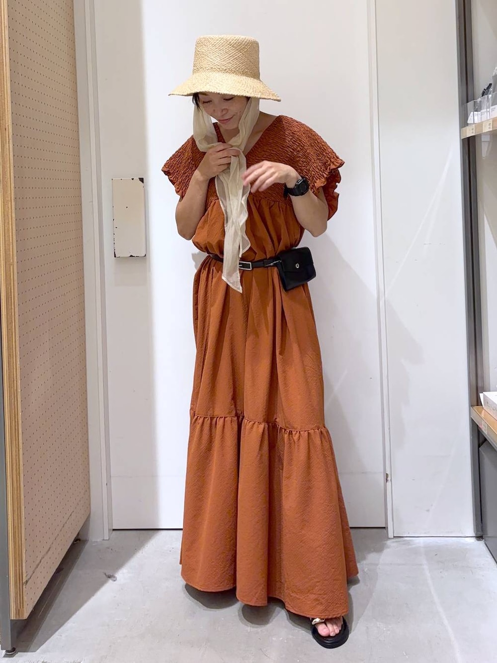 オレンジ系のワンピース、ブラック系のサンダル、ホワイト系のキャミソールを着用したレディースの夏コーディネートの3枚目の写真