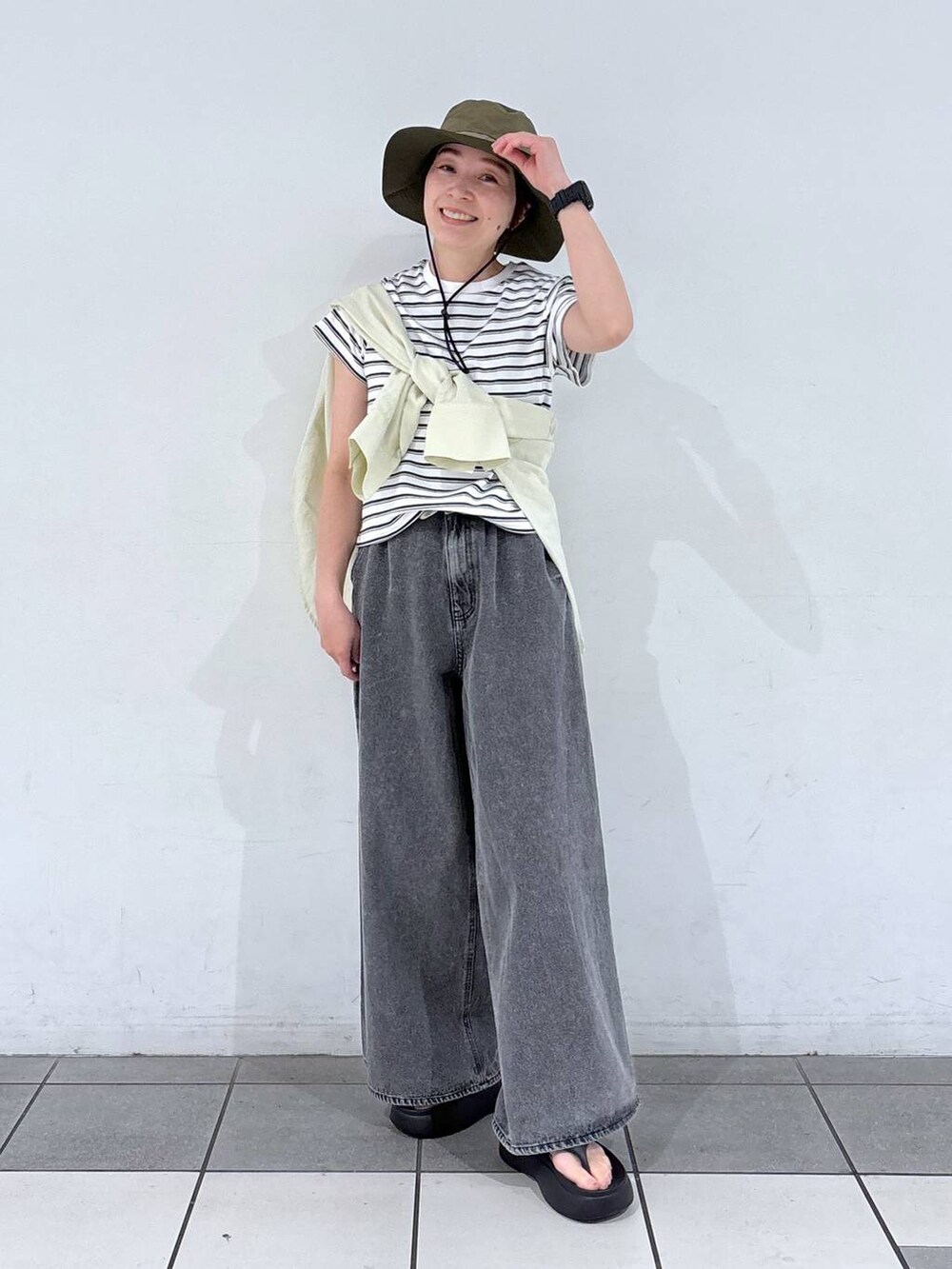 ブラック系のデニムパンツ、ブラック系のサンダルを着用したレディースの春コーディネートの3枚目の写真