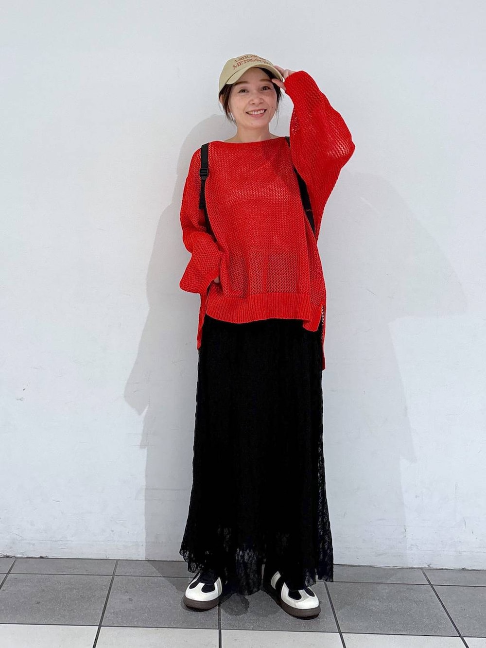 ブラック系のスニーカー、レッド系のニット/セーター、ブラック系のバックパック/リュックを着用したレディースの春コーディネートの4枚目の写真