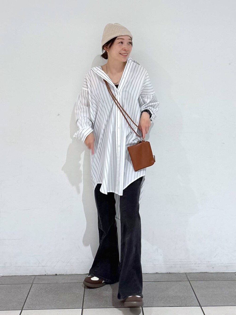 ホワイト系のスニーカー、ブラック系のデニムパンツ、ホワイト系のシャツ/ブラウスを着用したレディースの春コーディネートの2枚目の写真