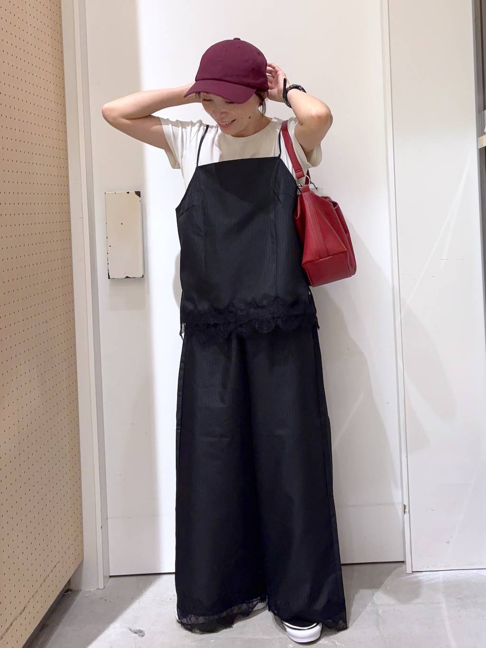 ブラック系のスラックス、ブラック系のキャミソール、レッド系のショルダーバッグを着用したレディースの夏コーディネートの4枚目の写真