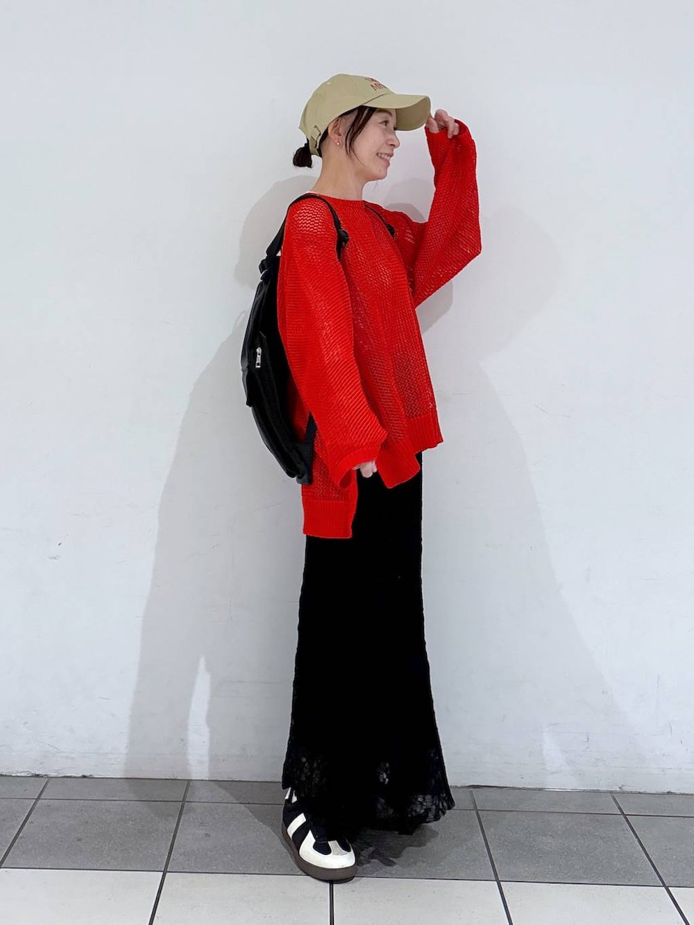 ブラック系のスニーカー、レッド系のニット/セーター、ブラック系のバックパック/リュックを着用したレディースの春コーディネートの3枚目の写真