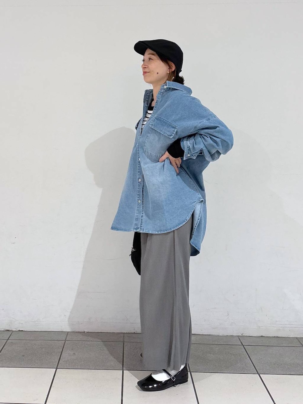 ホワイト系のニット/セーター、ブラック系のパンプス、ブルー系のシャツ/ブラウスを着用したレディースの春コーディネートの3枚目の写真